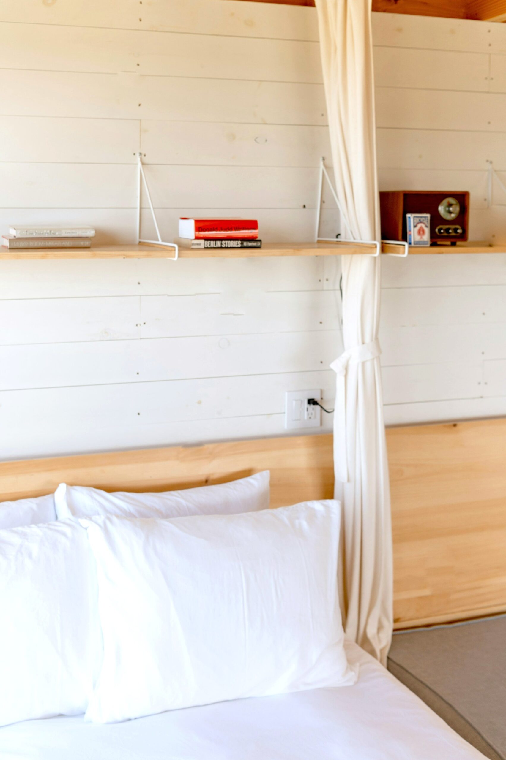White wood-paneled wall behind a crisp white bed