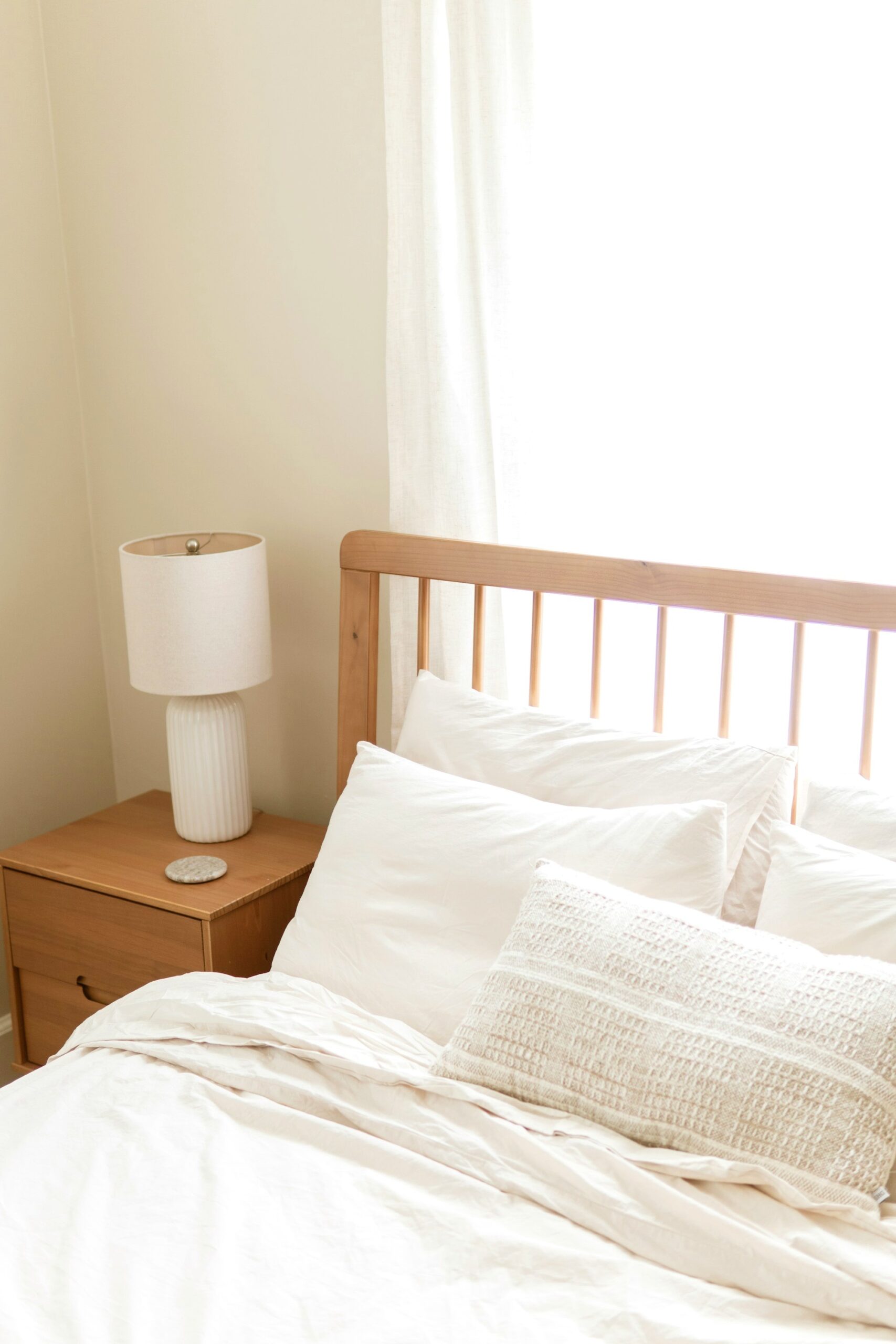 Simple uncluttered bedroom with a light wood bed and white bedding
