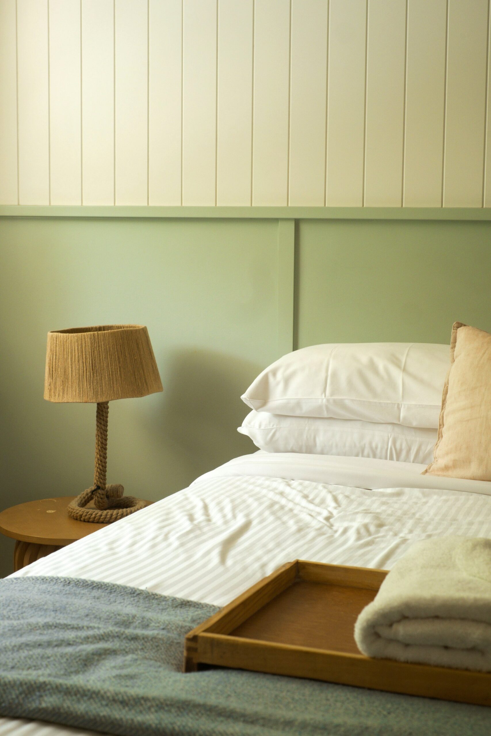 Beach cottage bedroom with beadboard wall, sage green paint and woven lamp