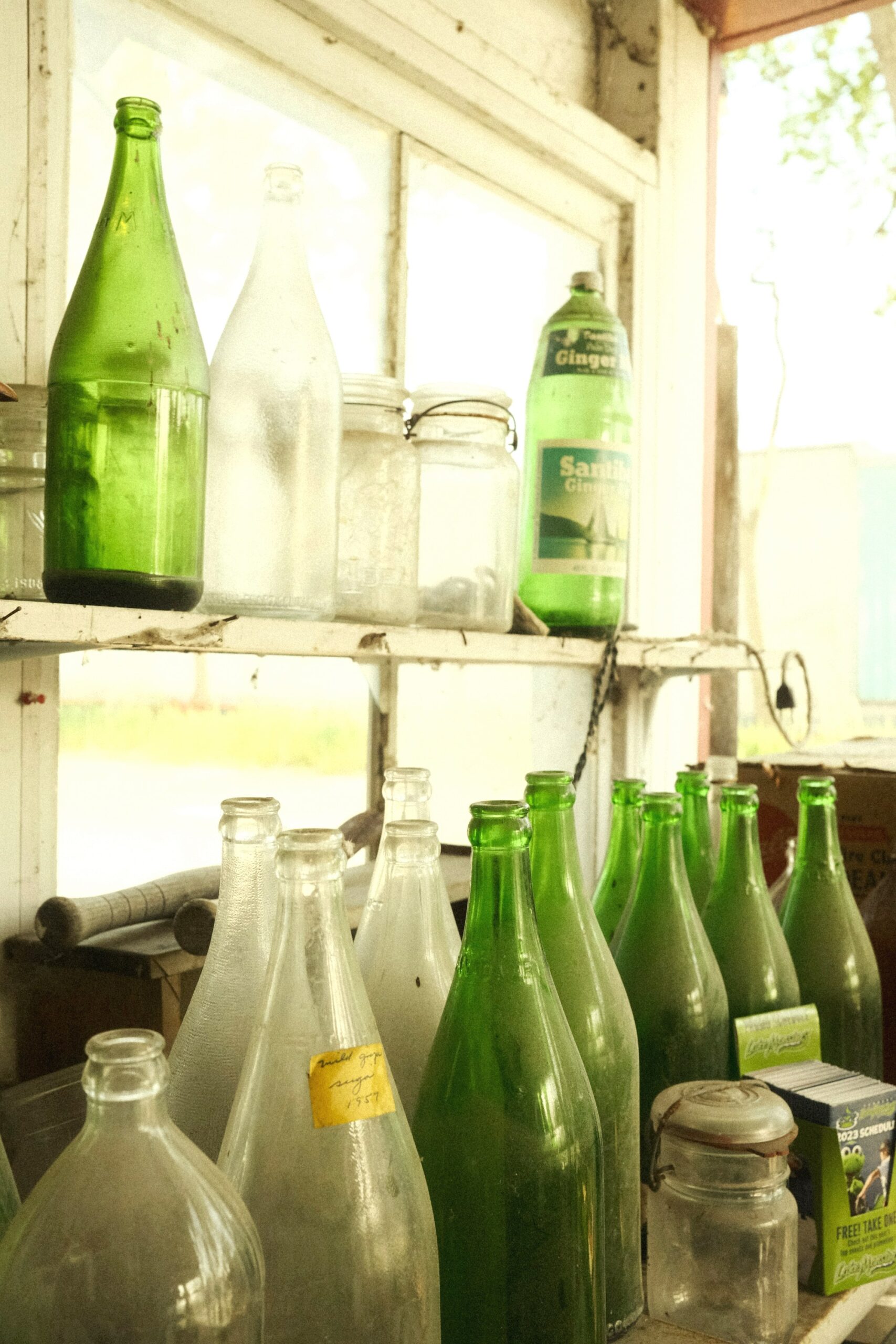 Green and clear glass bottles on a sunny shelf