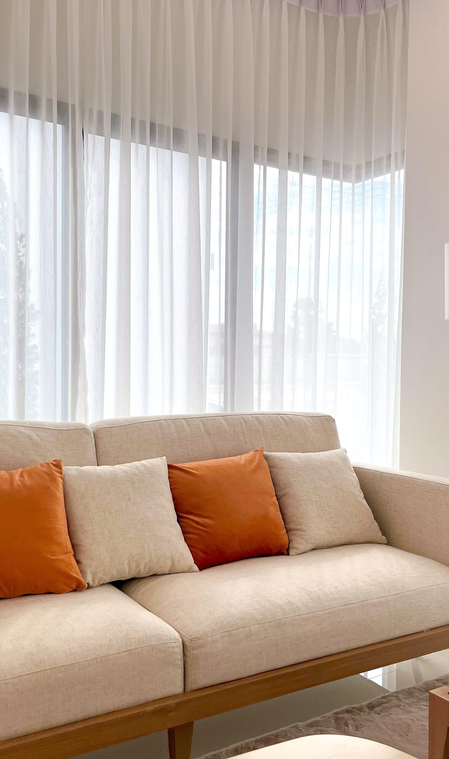 Sheer white curtains beside a cream sofa