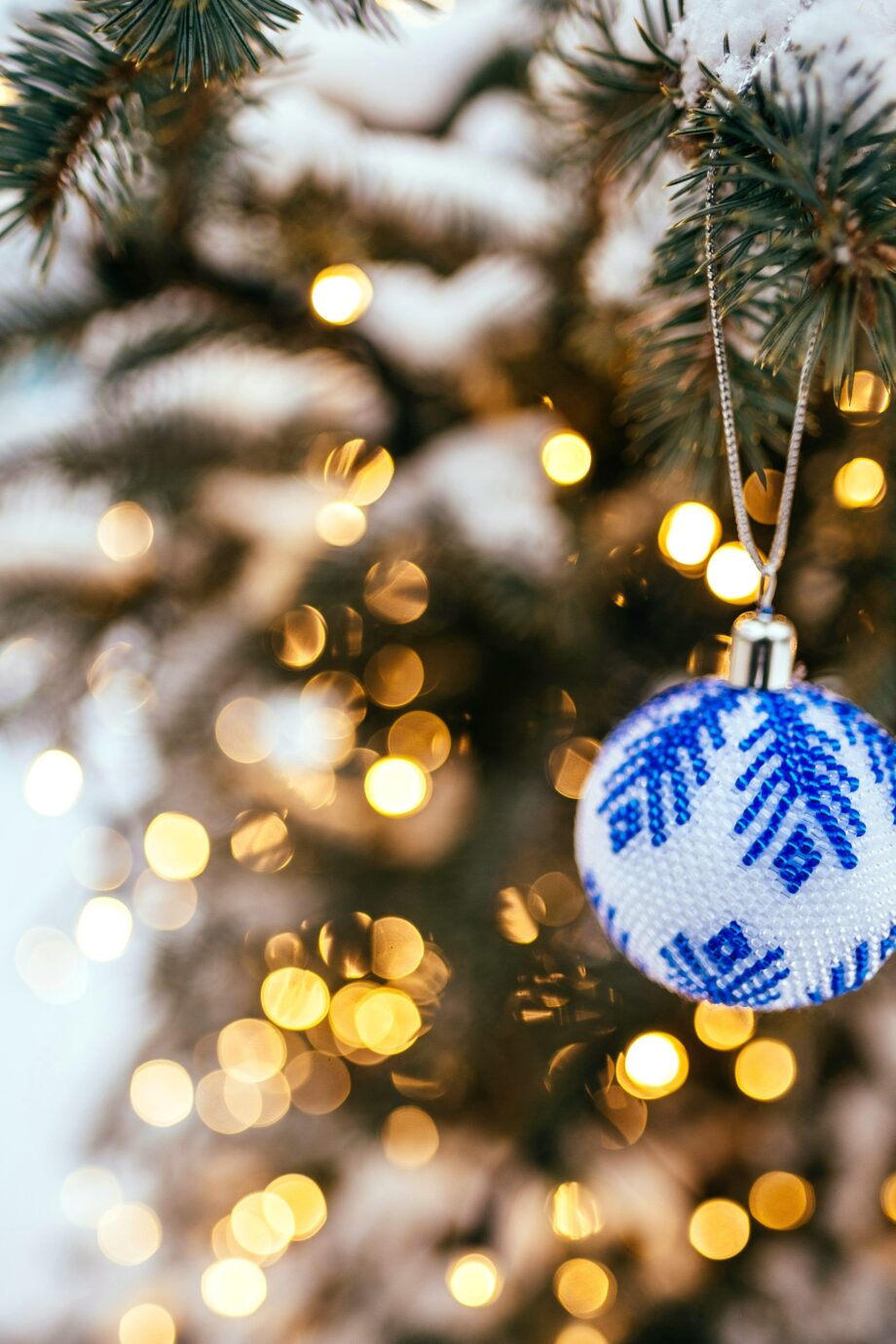 Blue and white ornament glowing among Christmas lights